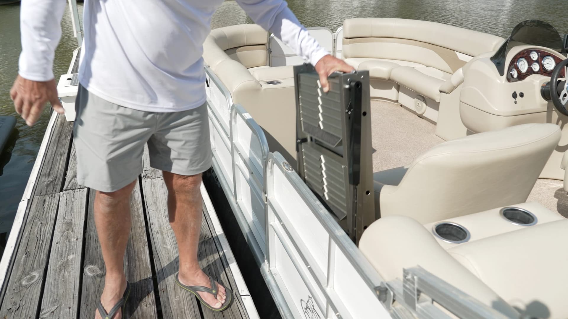 A boater folding the nautiDAWGS ladder flat against a pontoon rail